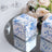 Floral patterned gift boxes on a mirrored surface with roses in the background.
