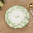 Floral decorative plate on wooden table with gold and white utensils.