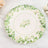 Floral decorative plate with green leaves and white flowers on a marble surface.