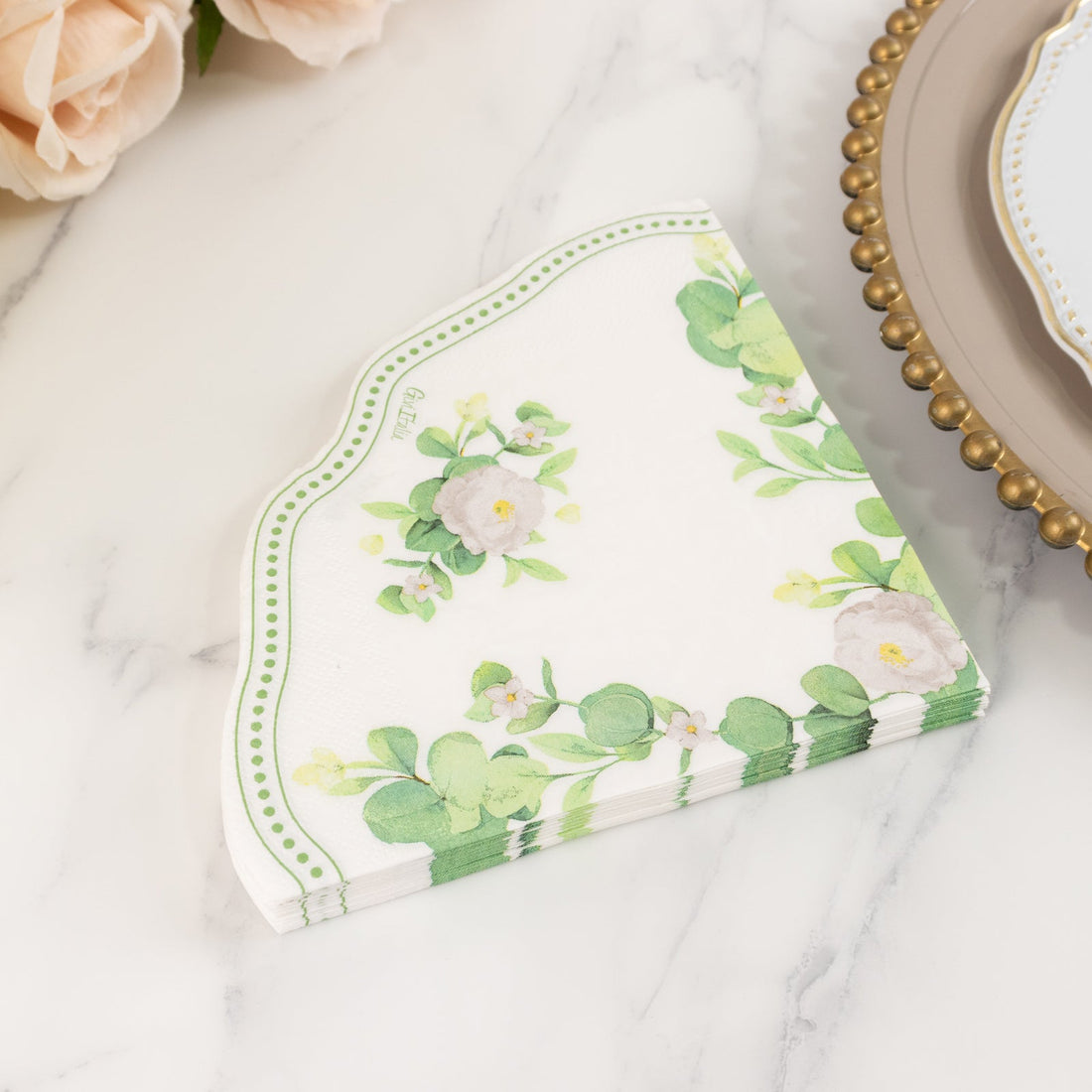 Floral paper napkins stacked with green leaves and white flowers design.