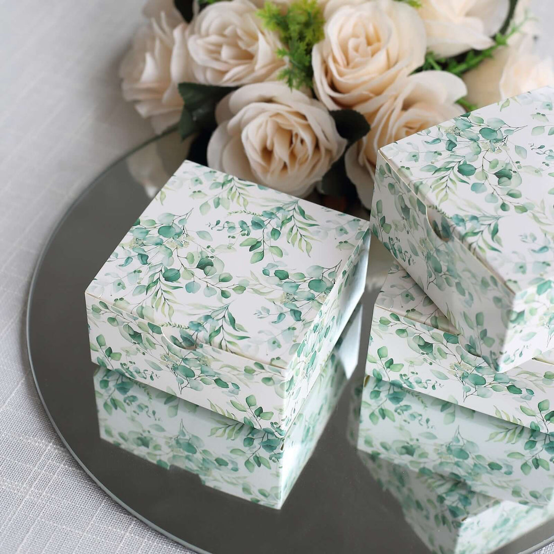 Decorative gift boxes with floral design on a mirrored surface.