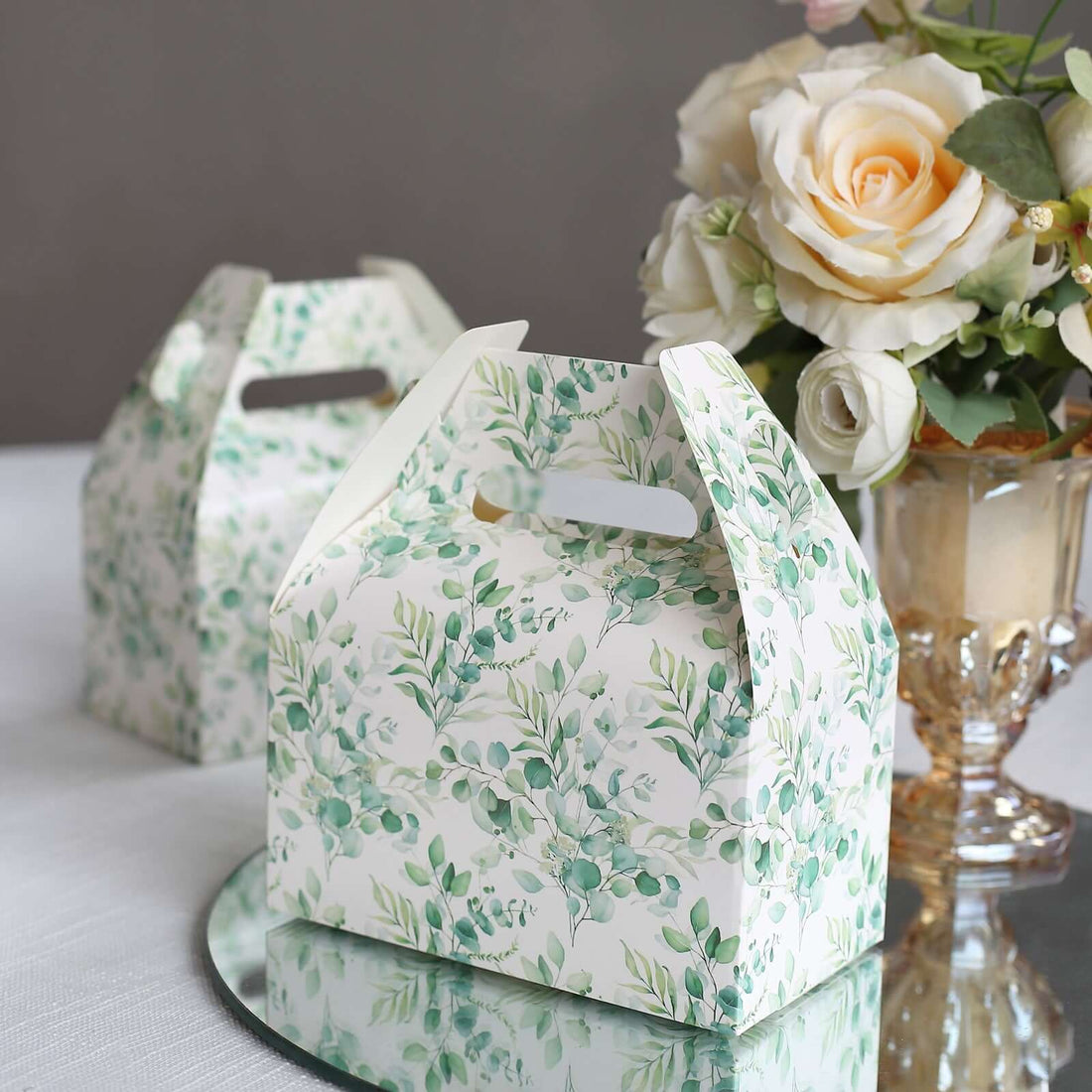 Decorative floral gift boxes on a table with a bouquet of roses.