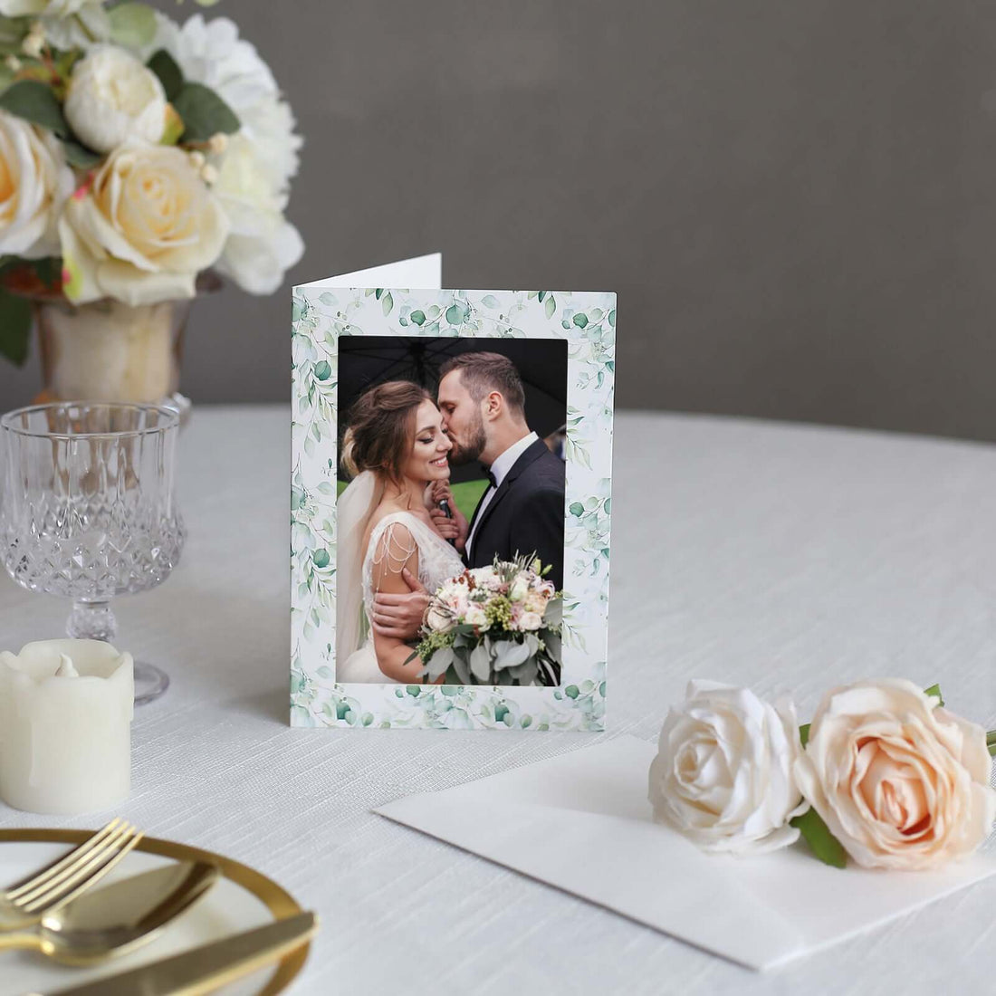 Wedding invitation card with floral design on a table with roses and decor.
