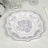 Lavender floral decorative plate on a textured tablecloth.