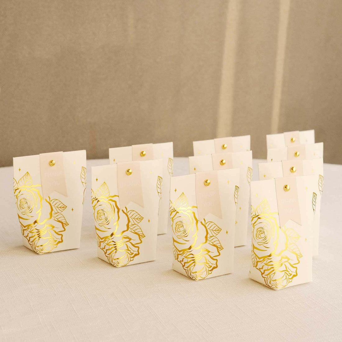Gold-embellished gift bags with rose design displayed in a row.