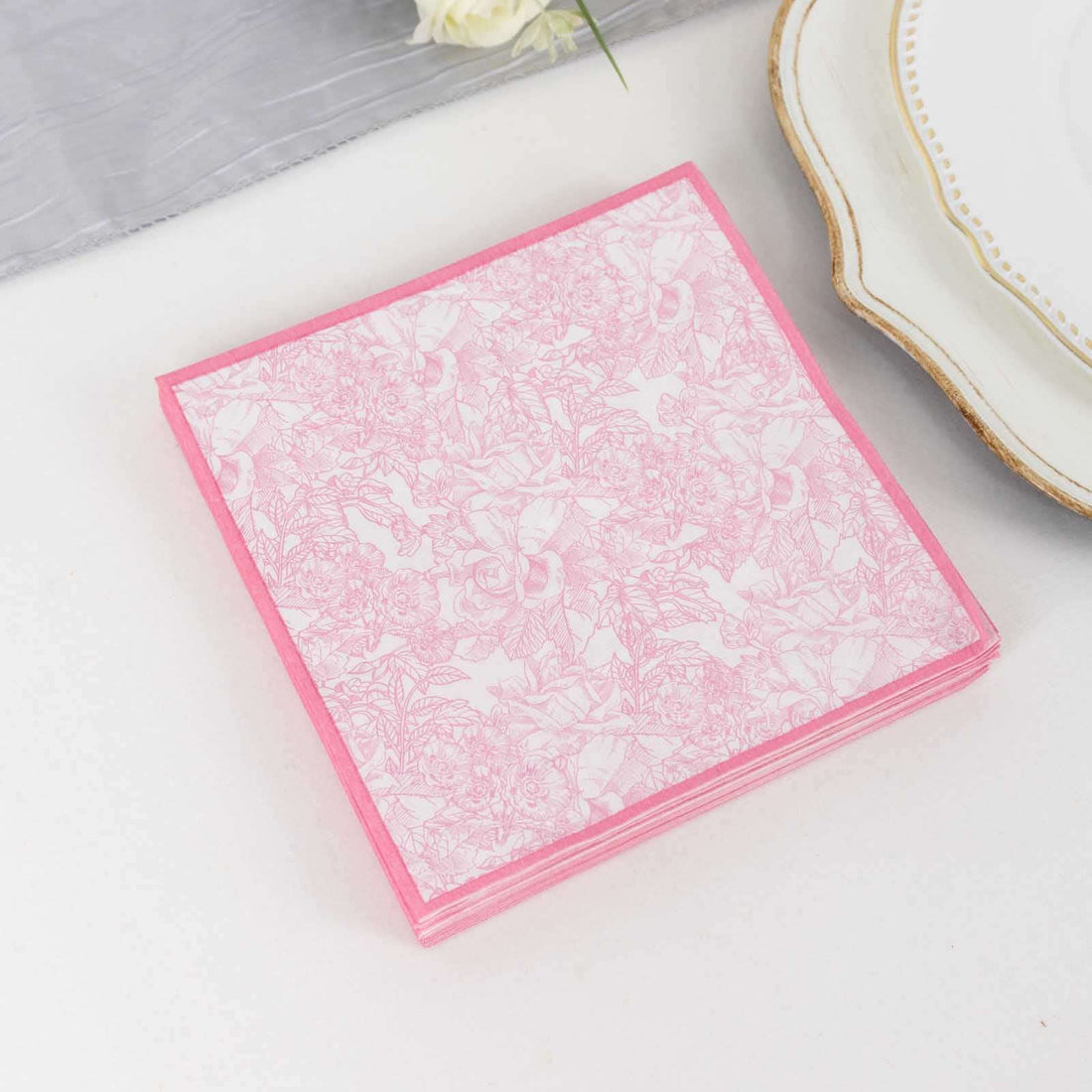 Pink floral-patterned napkins stacked on a table.
