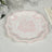 Pink floral decorative plate on a textured tablecloth.