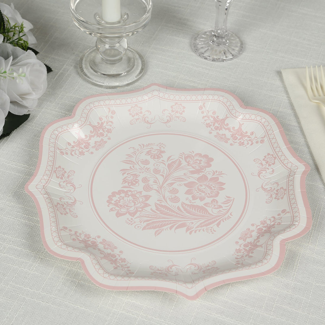 Elegant pink floral patterned plate on a textured table setting.