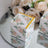 Floral gift box on a mirrored surface with roses in the background.