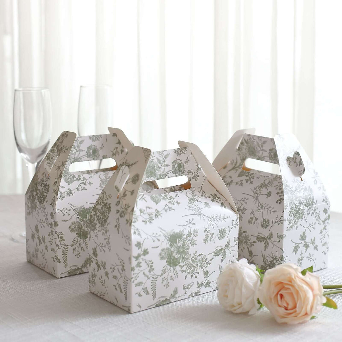 Floral patterned takeout boxes on a table with glasses and flowers.