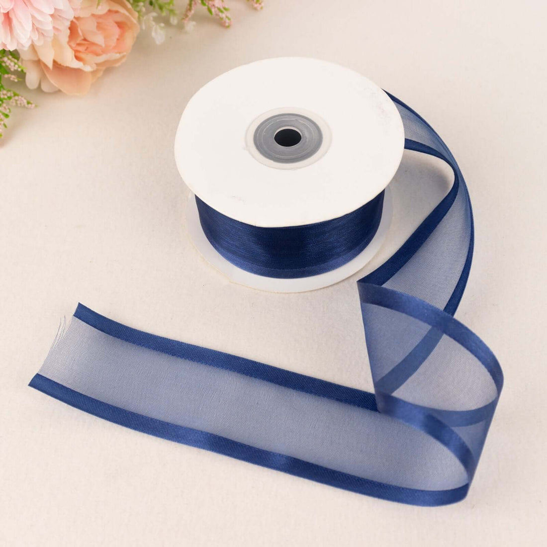 Navy blue sheer ribbon on a spool with a flowing tail