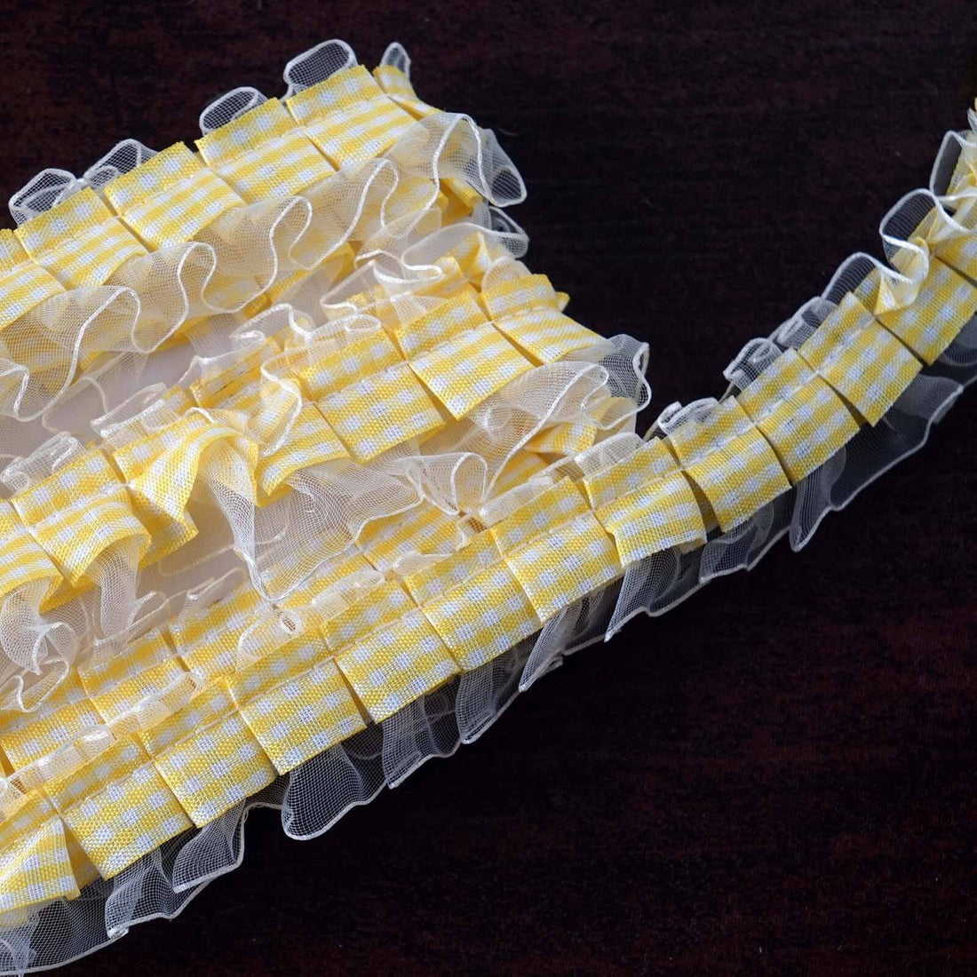Yellow gingham ruffled ribbon on a dark surface.