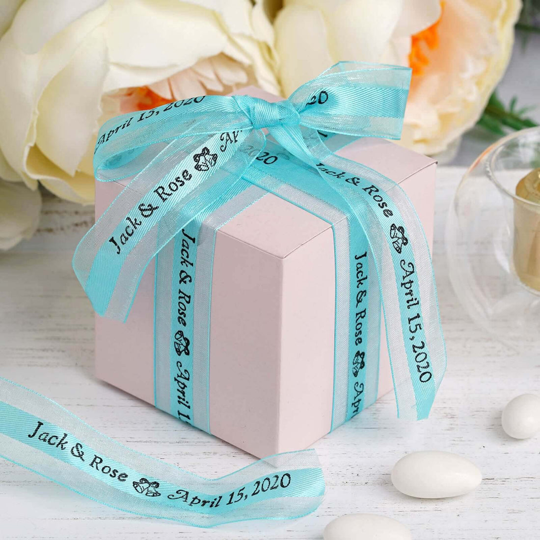 Personalized wedding favor box with blue ribbon and custom text.