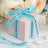 Personalized wedding favor box with blue ribbon and custom text.