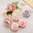 Assorted artificial flowers in pastel colors on a light surface.