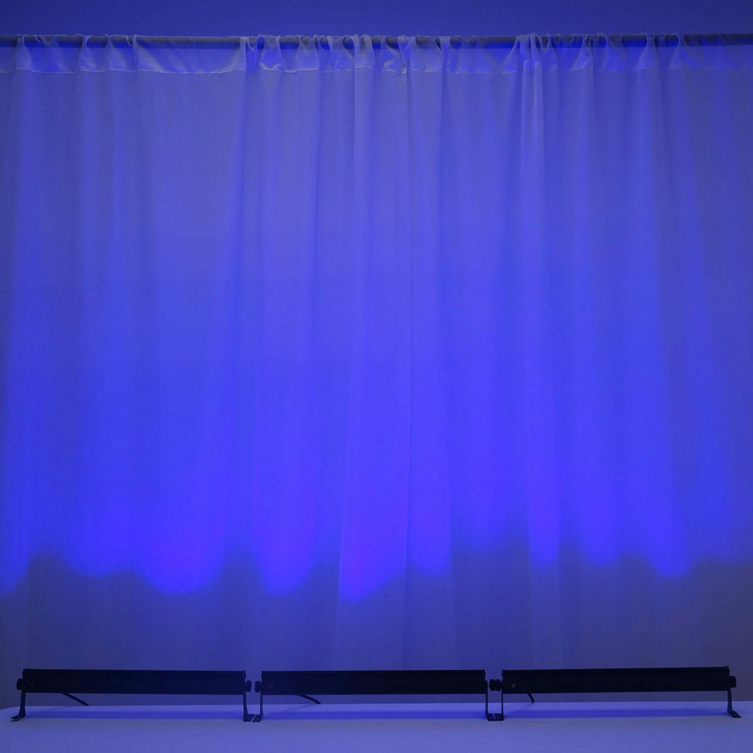 Blue illuminated backdrop with black stands in front.