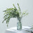 Eucalyptus and white flower arrangement in a clear vase.
