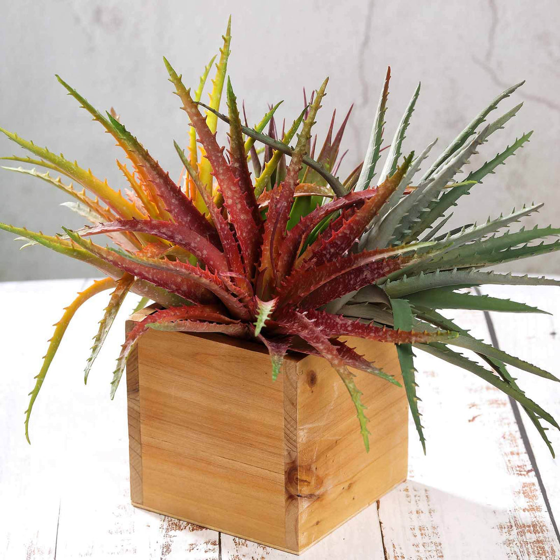 Colorful faux aloe vera plant in a wooden planter.