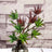 Colorful artificial succulent arrangement in a glass vase.