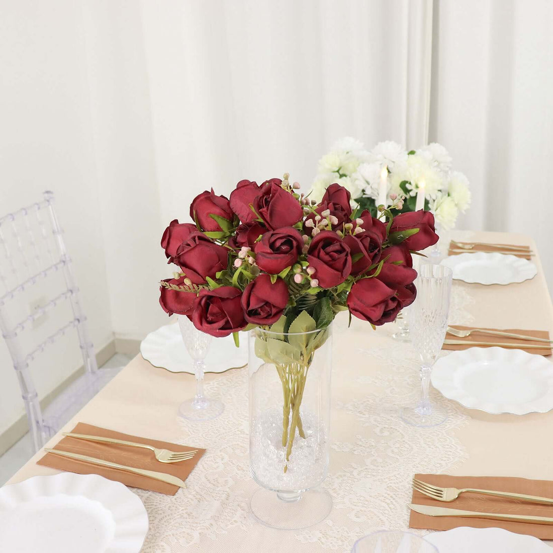 Red roses bouquet in a vase on a dining table setting.