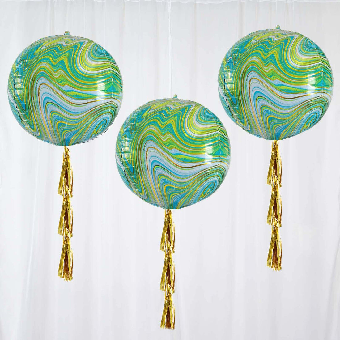 Colorful marbled balloons with gold tassels hanging against a white backdrop.