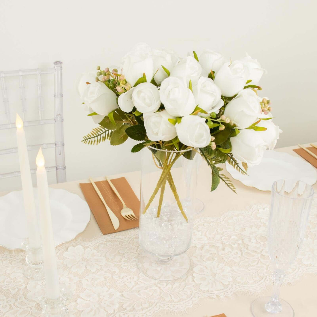 White rose bouquet in a clear vase on a beautifully set dining table.