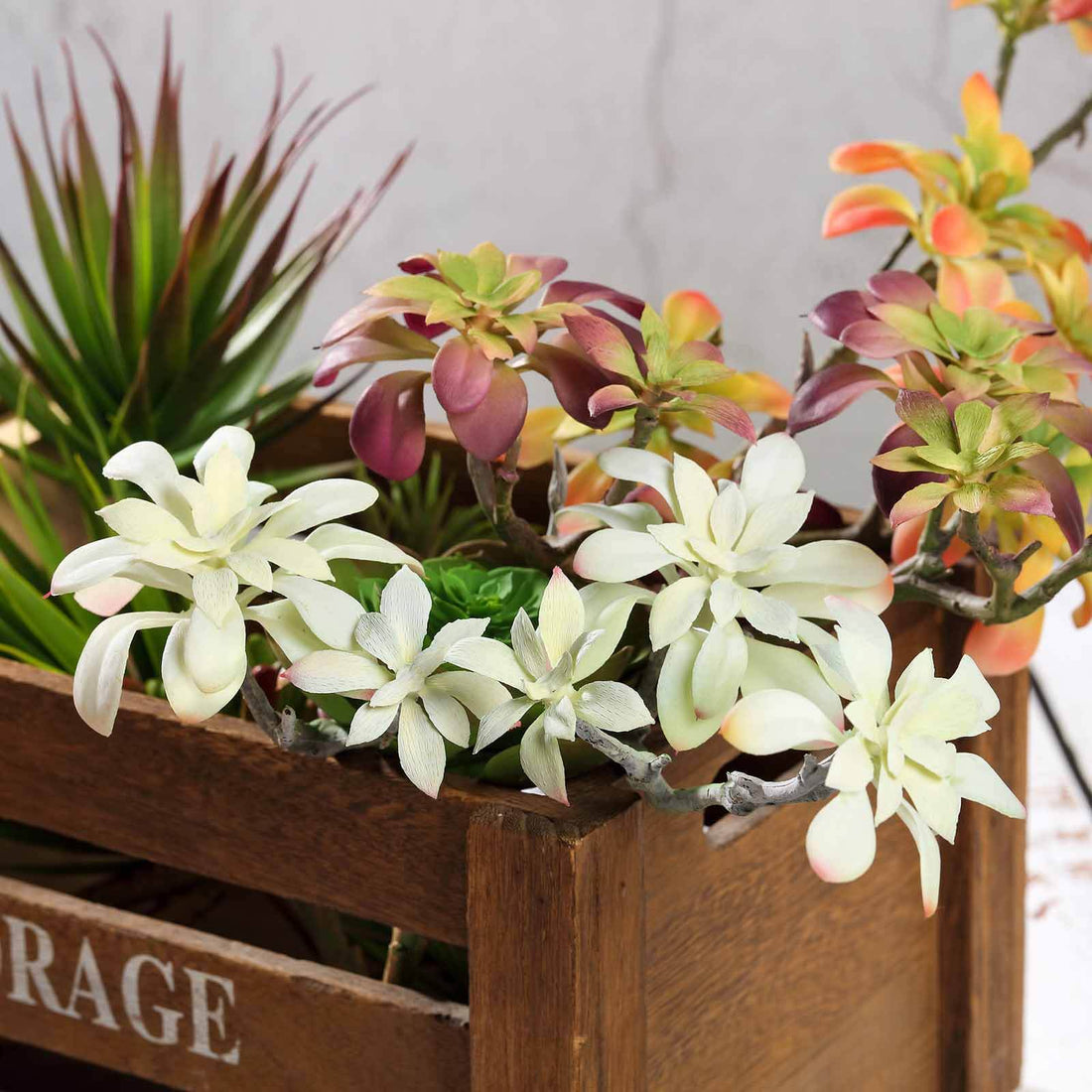 Colorful artificial succulent arrangement in a wooden crate.