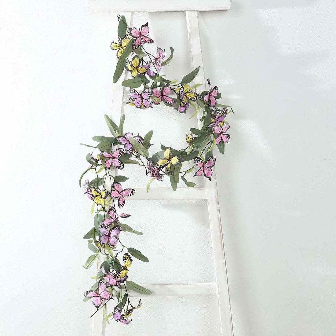 Colorful butterfly garland draped on a white ladder