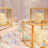 Gold-framed glass candle holders with white candles and colorful confetti.