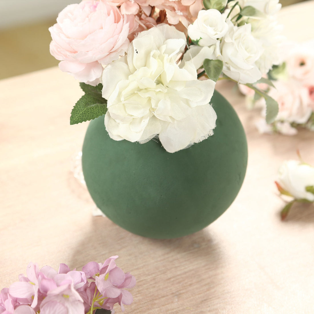 Green vase with flowers on a wooden surface.