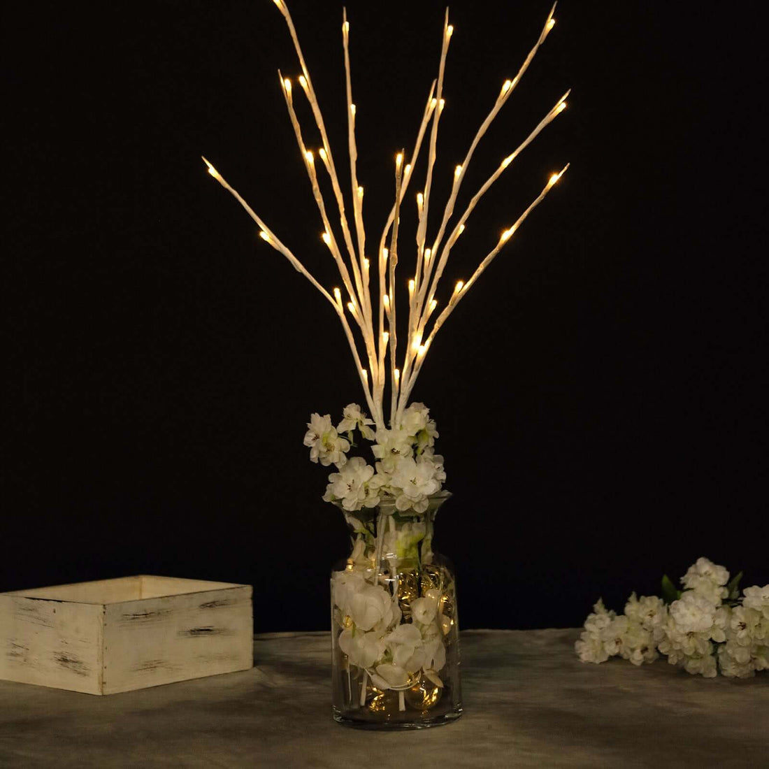 Decorative vase with LED twigs and flowers on a dark background.
