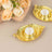 Gold leaf-shaped candle holders with tea lights beside soft pink roses.