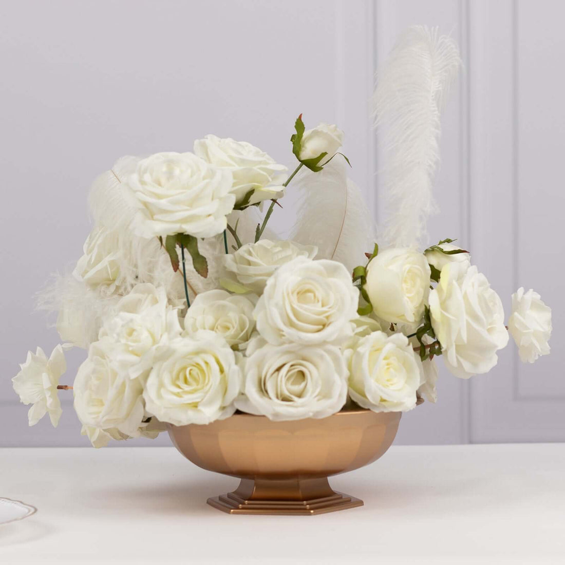 Elegant white rose arrangement in a copper bowl with feathers.