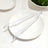 Clear kitchen tongs on a white plate with salad in the background.