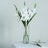 Artificial white flowers in a clear vase on a table.