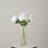 White artificial flowers in a clear vase on a round table.