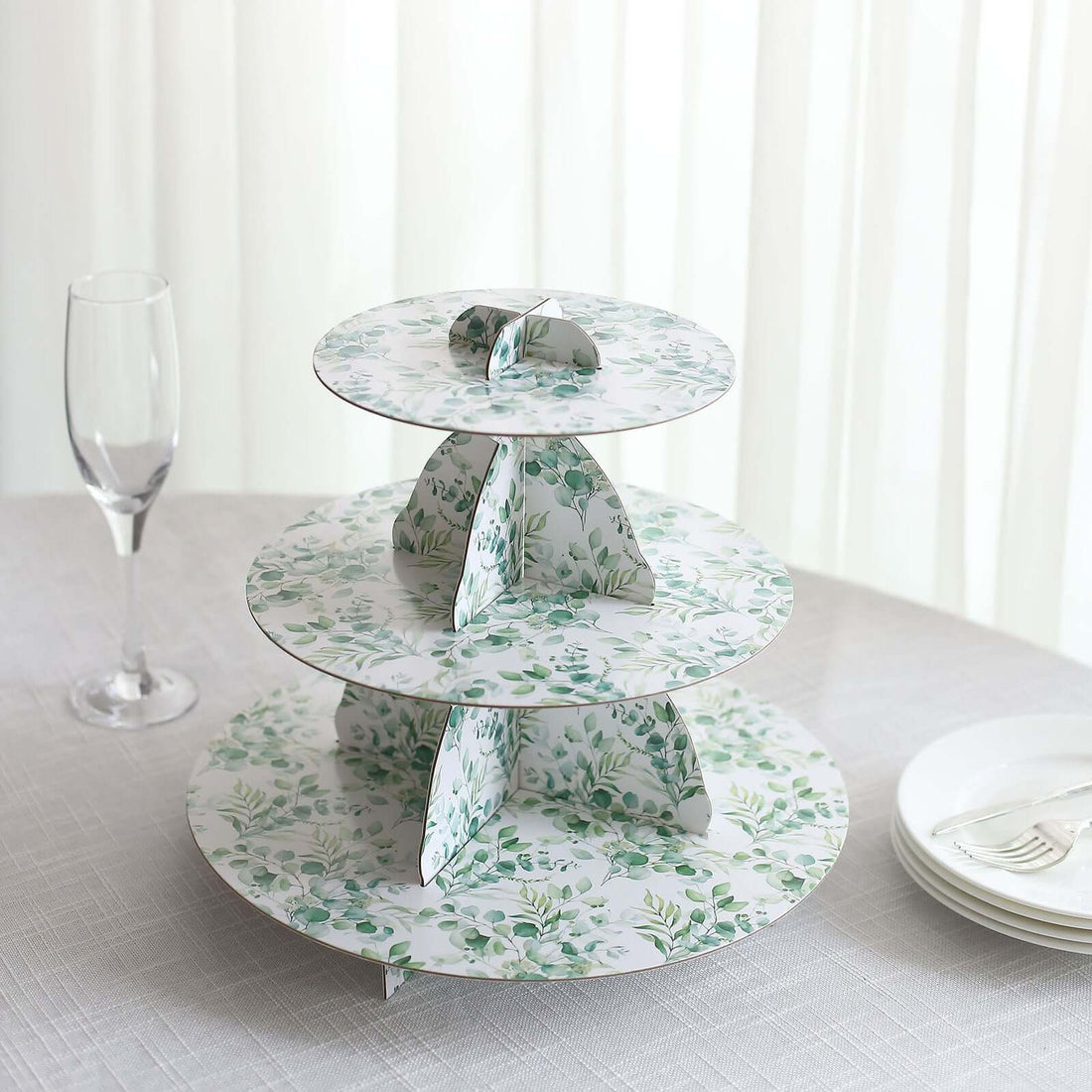 Three-tiered cake stand with floral design on a table.