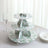 Three-tiered cake stand with floral design on a table.