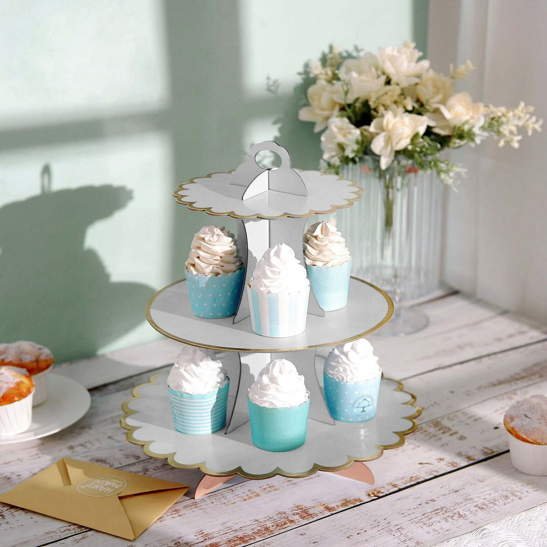Cupcake stand with decorative cupcakes in pastel colors on a wooden table.