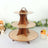 Three-tier wooden dessert stand with decorative plates and handle.