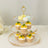 Three-tiered dessert stand with cupcakes and macarons.