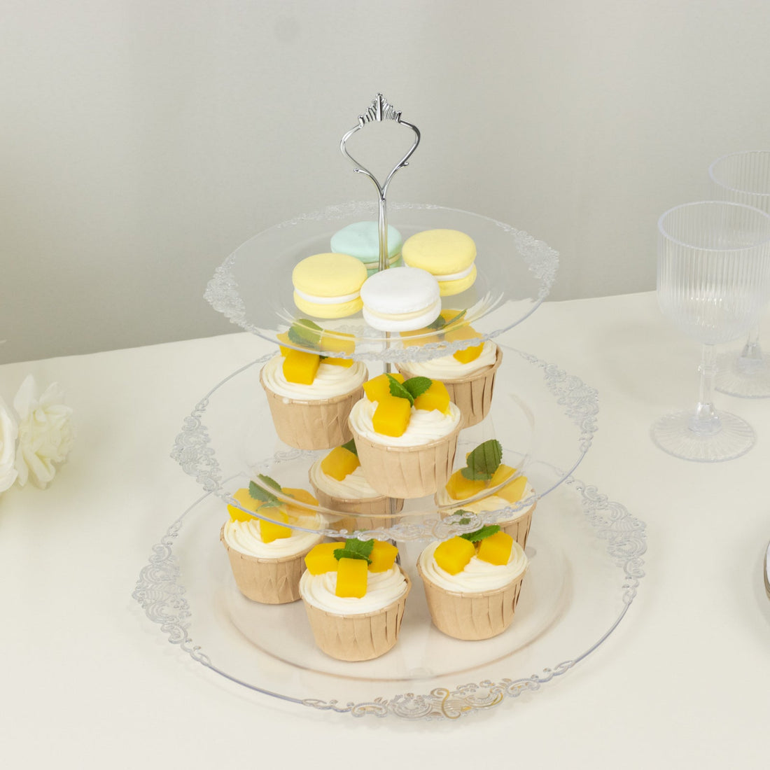 Three-tiered dessert stand with cupcakes and macarons.
