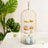 Gold cupcake stand with assorted cupcakes and decorative plants in the background.