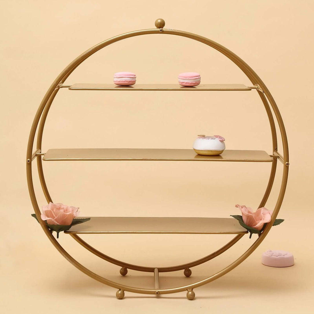 Gold circular shelf with pink desserts and floral accents.