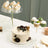 Elegant cake and cupcakes displayed on clear stands at a dessert table.