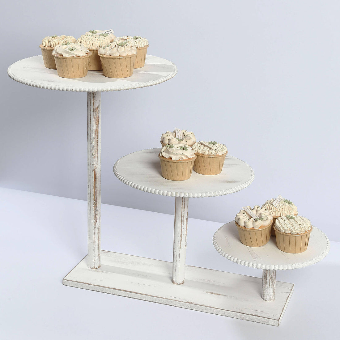 Assorted cupcakes displayed on a tiered wooden stand.