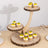 Wooden cake stand with mini cupcakes topped with mango and mint leaves.