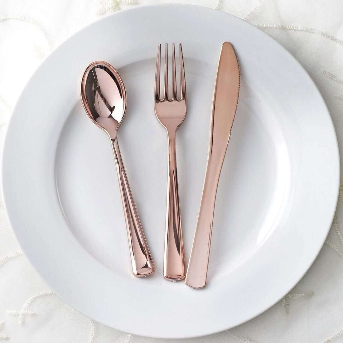 Rose gold cutlery set on a white plate.