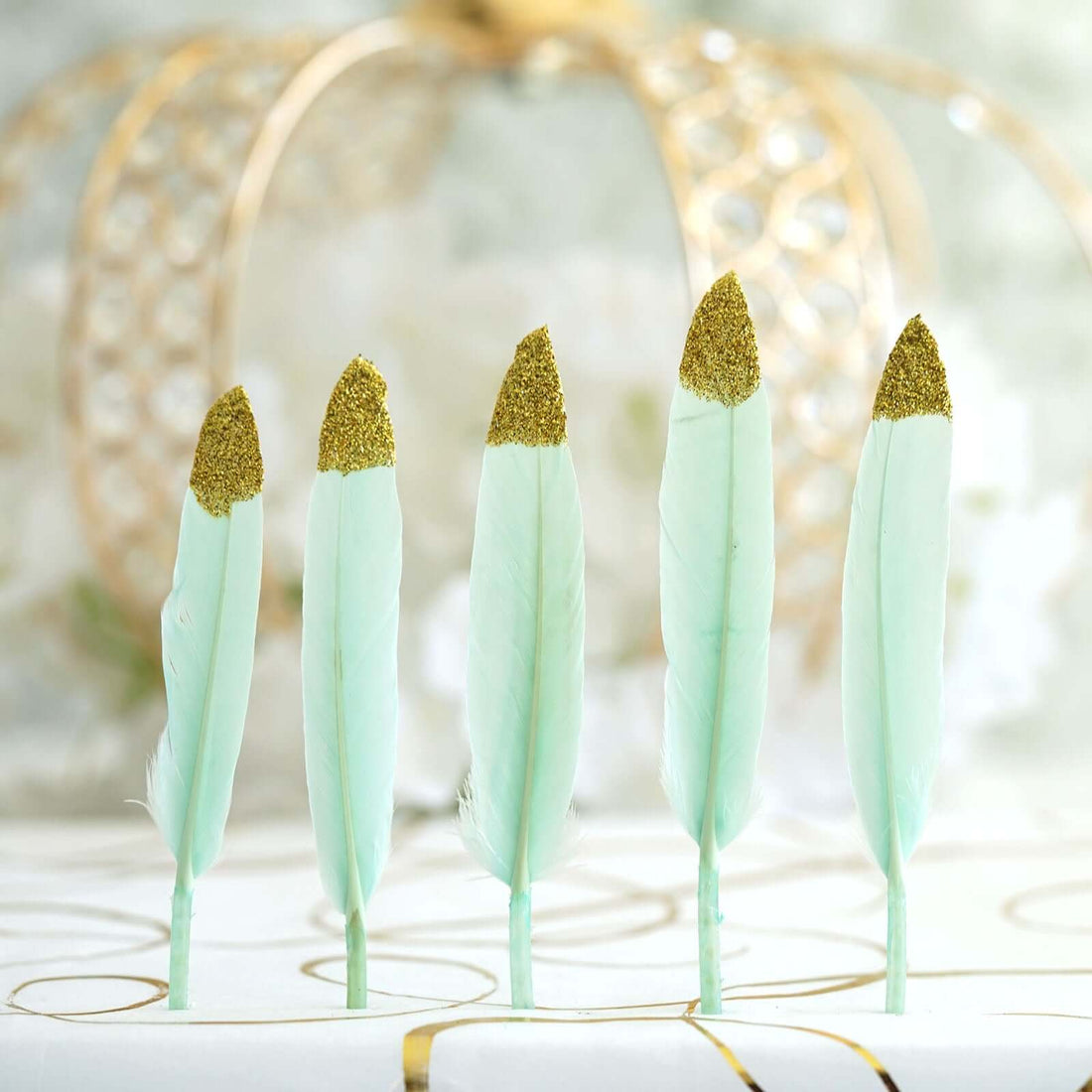 Mint green decorative feathers with gold tips on a white background.
