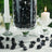 Black decorative crystals in a glass vase with candles on a table.